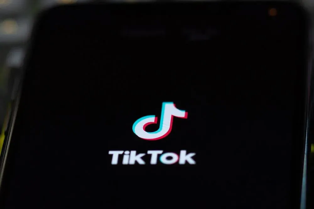 Un smartphone affichant un fil Pour Toi TikTok avec une publicité vidéo verticale courte d'une marque de mode en plein écran.
