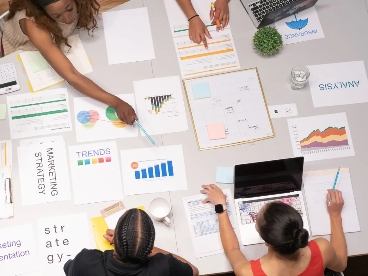 Equipo creativo de publicidad colaborando en estrategia de marketing con documentos de análisis y tendencias