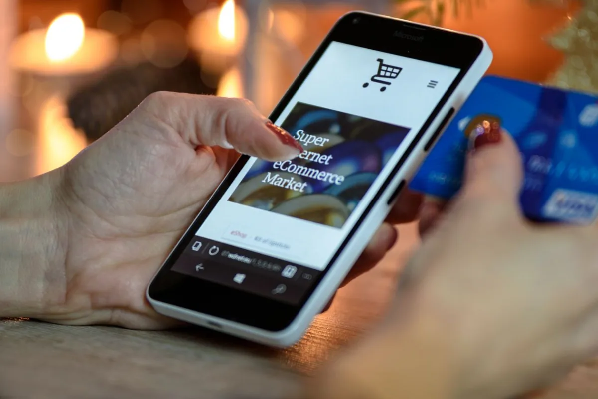 Personne finalisant un achat en ligne avec une carte bancaire depuis son smartphone